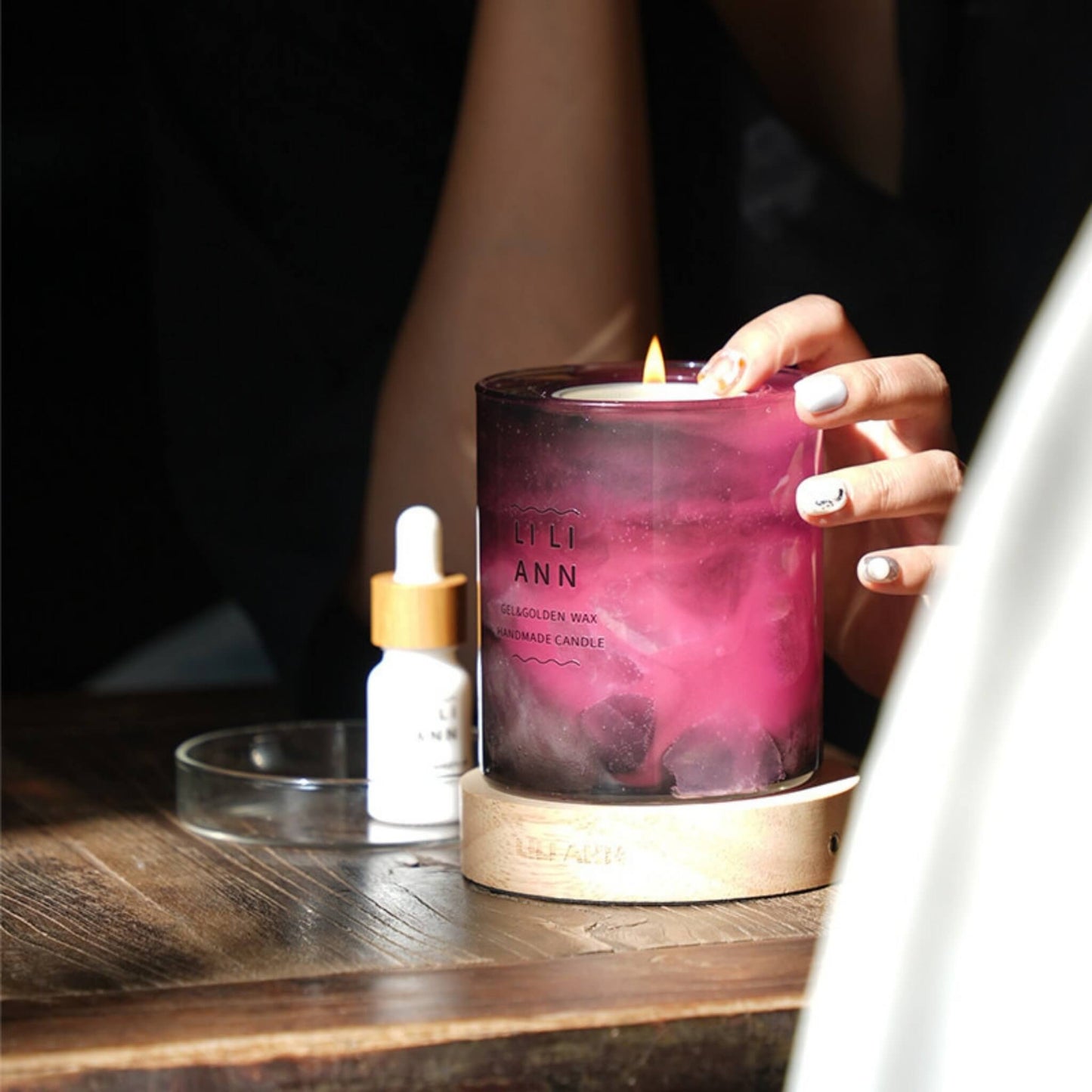 Woman's hand touching the lit Dawn Vessel, creating a romantic evening atmosphere.